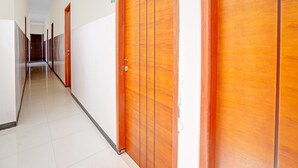 A hallway with wooden doors and a tiled floor. - OYO Flagship  90789 Genteng Residence (Surabaya)