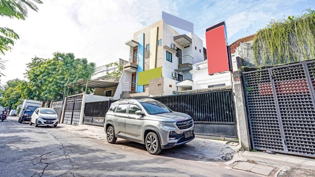 A modern building with a multi-story structure, a gated entrance, and a parked car in front. - OYO Flagship  90789 Genteng Residence (Surabaya)