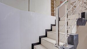 A staircase with white steps and black edges, metal handrails, and a sign above indicating no smoking. - OYO Flagship  90789 Genteng Residence (Surabaya)
