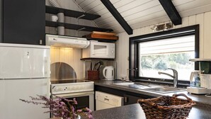 A compact kitchen with a stove, microwave, and sink. - 6 Person Holiday Home in Blavand (Blavand)