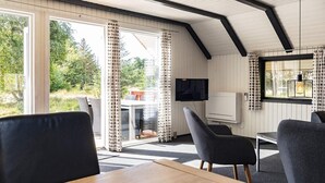 A cozy room with a wooden table, two chairs, a TV, and a window with curtains. - 6 Person Holiday Home in Blavand (Blavand)
