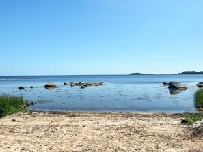 A beach with clear water, scattered rocks, and a distant landmass. - 4 Star Holiday Home in Solvesborg (Sölvesborg)