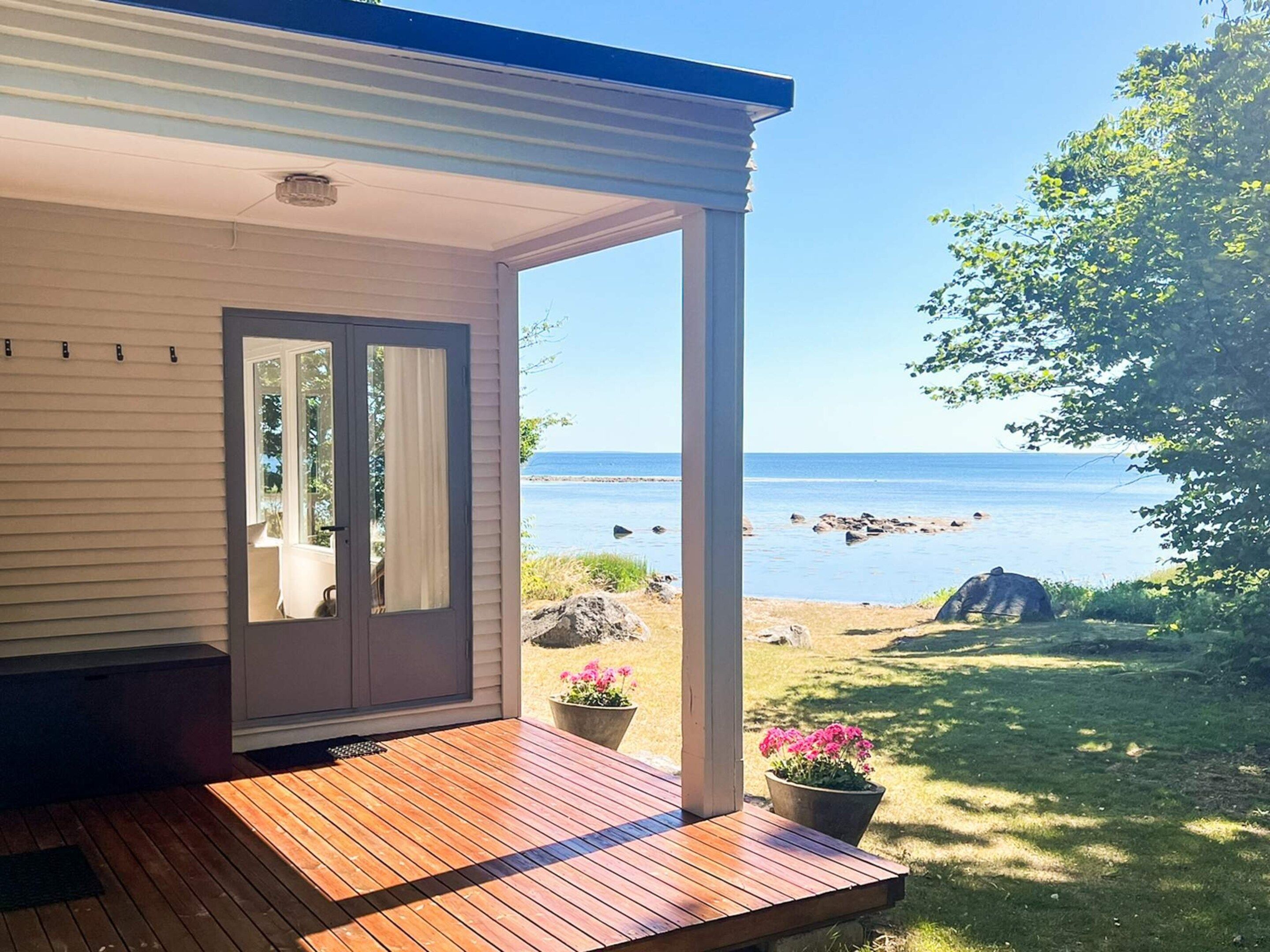 A wooden deck with a view of the sea and a garden with a potted plant.