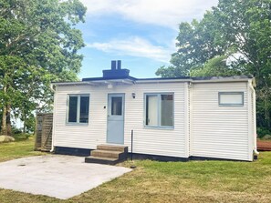 A single-story mobile home with a front door, two windows, a chimney, and a small porch. - 4 Star Holiday Home in Solvesborg (Sölvesborg)