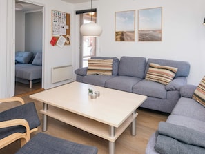 A modern living room with a grey sofa, a wooden coffee table, and a wall-mounted light fixture.