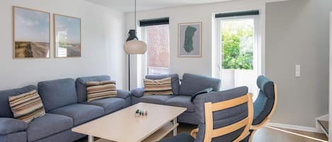 A modern living room with a sectional sofa, a wooden coffee table, and a rocking chair.