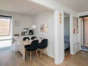 A modern kitchen with a dining area, a coffee machine, and a painting on the wall.