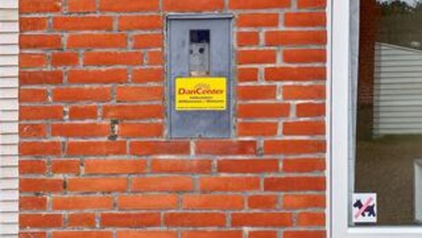 Een bakstenen muur met een technische kast en een bord waarop 'DanCreevy' staat.