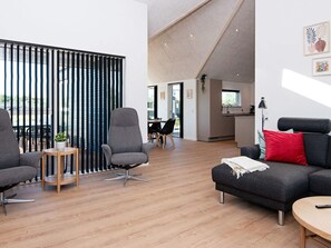 A modern living space with a dining area, kitchen, and a balcony with vertical blinds.
