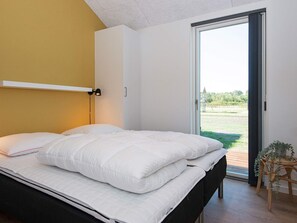 A bedroom with a bed, a bedside lamp, a sliding glass door, and a small plant.