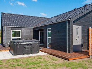 A modern house with a hot tub, a covered patio, and a sauna.