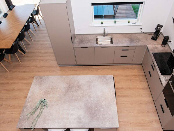 A modern kitchen with a central island, a built-in sink, and a window above the countertop.