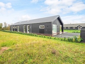 En moderne bygning med mørk facade, store vinduer og et skråt tag.