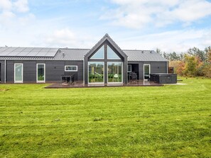 Une maison moderne dotée d’une grande terrasse, d’un patio couvert et d’un vaste jardin.