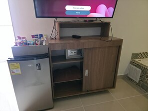 A kitchenette with a refrigerator, microwave, and a flat-screen TV mounted above the counter. - Infinity Hotel (Medellín)