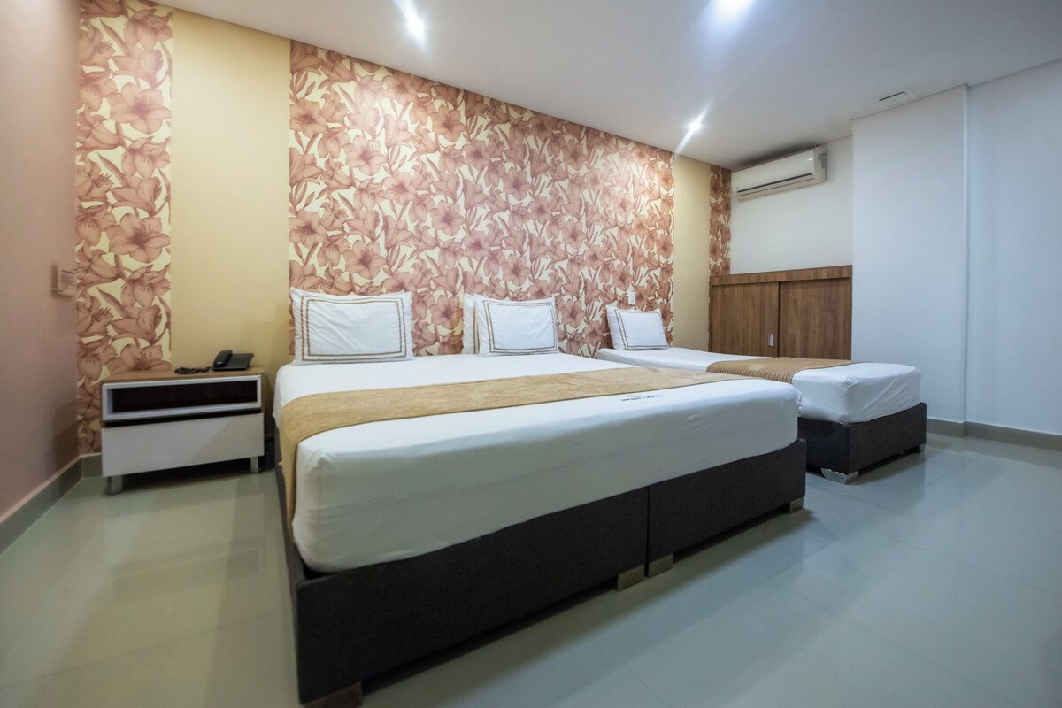 A hotel room with two beds, a nightstand, and a wardrobe.