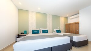 A hotel room with two beds, a nightstand, and a wooden wardrobe.