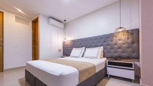 A modern bedroom with a tufted headboard, a bedside table, and a hanging light fixture.