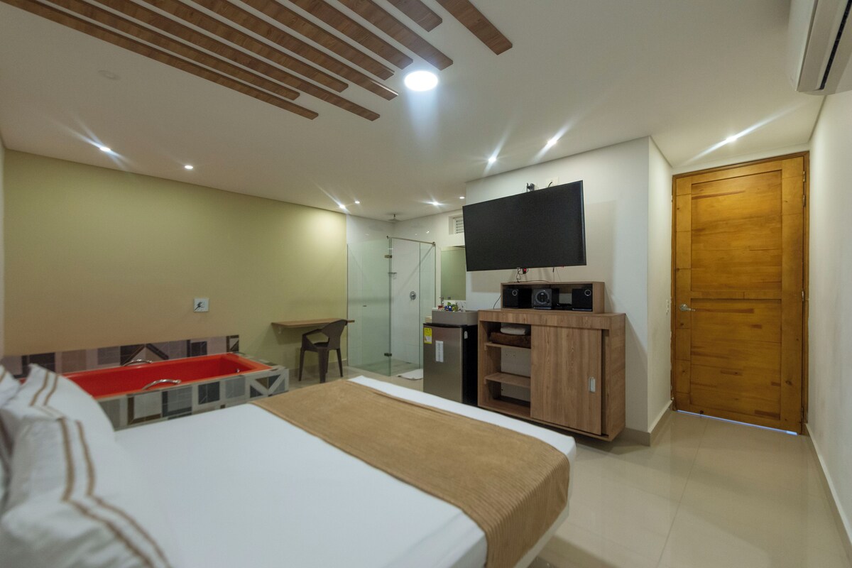 A hotel room with a bed, a desk, a TV, and a wardrobe.
