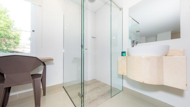 A modern bathroom with a glass-enclosed shower, a large white sink, and a mirror above it.