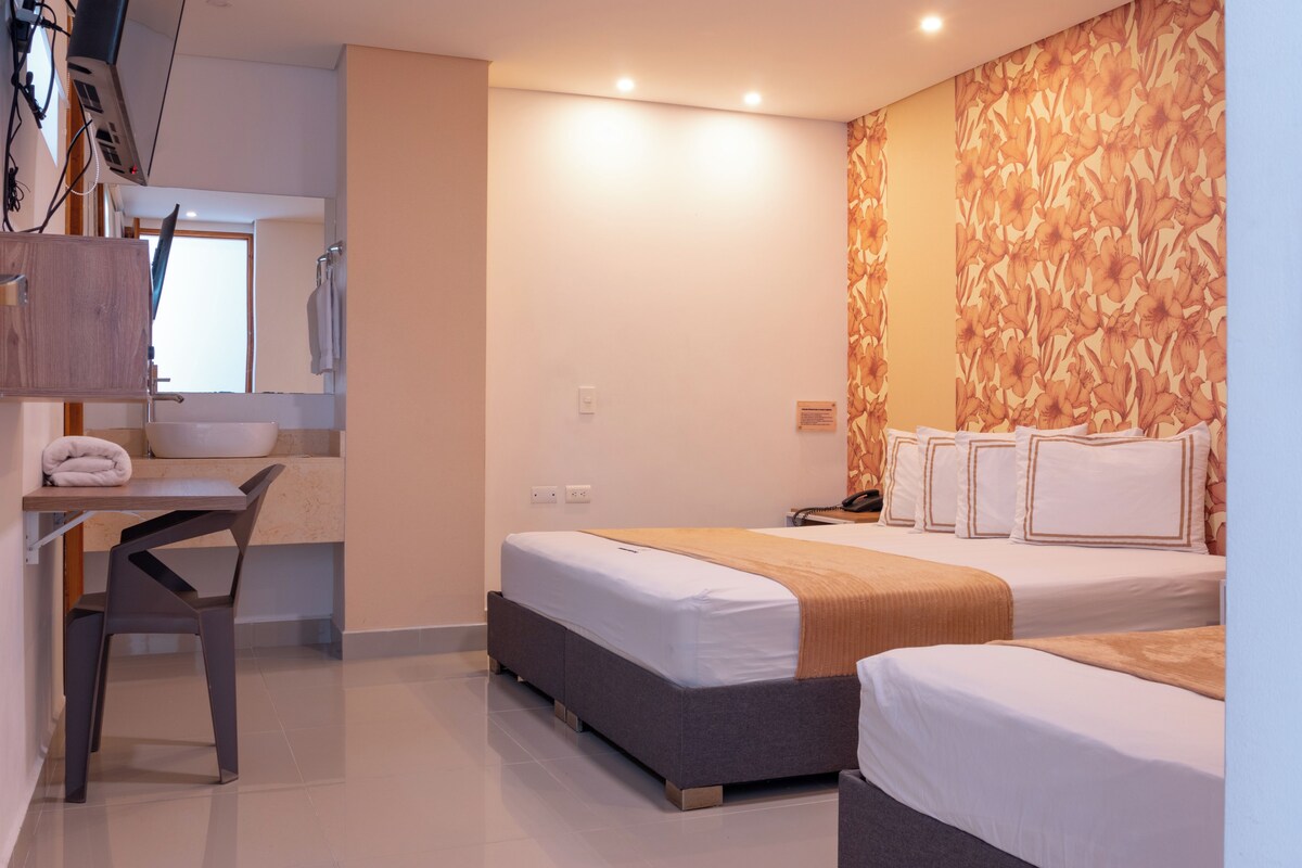 A hotel room with two beds, a desk, and a chair.