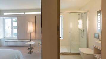 A modern bathroom with a glass shower, a toilet, and a vanity with a mirror.