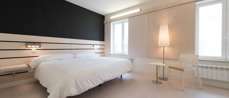 A modern bedroom with a bed, bedside tables, a chair, and a floor lamp.