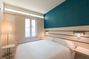 A modern hotel room with a large bed, a bedside table, a lamp, and a window with blinds. - Boreal Viento Norte (Burgos)