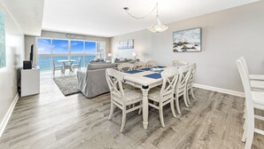 Un vaste espace de vie comprenant un coin repas avec une table et des chaises, et offrant une vue sur l’océan.