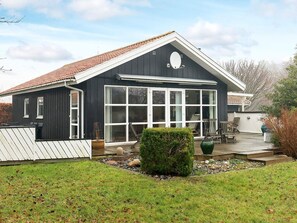 Et tosset etagehus med et stort vindue mod gaden, en overdækket veranda og en velplejet have.