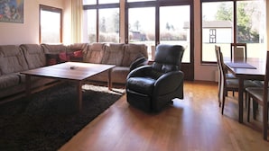 A spacious living room with a wooden ceiling, large windows, a leather sofa, a coffee table, and a dining area with a table and chairs. - 6 Person Holiday Home in Kirke Hyllinge (Kirke Hyllinge)