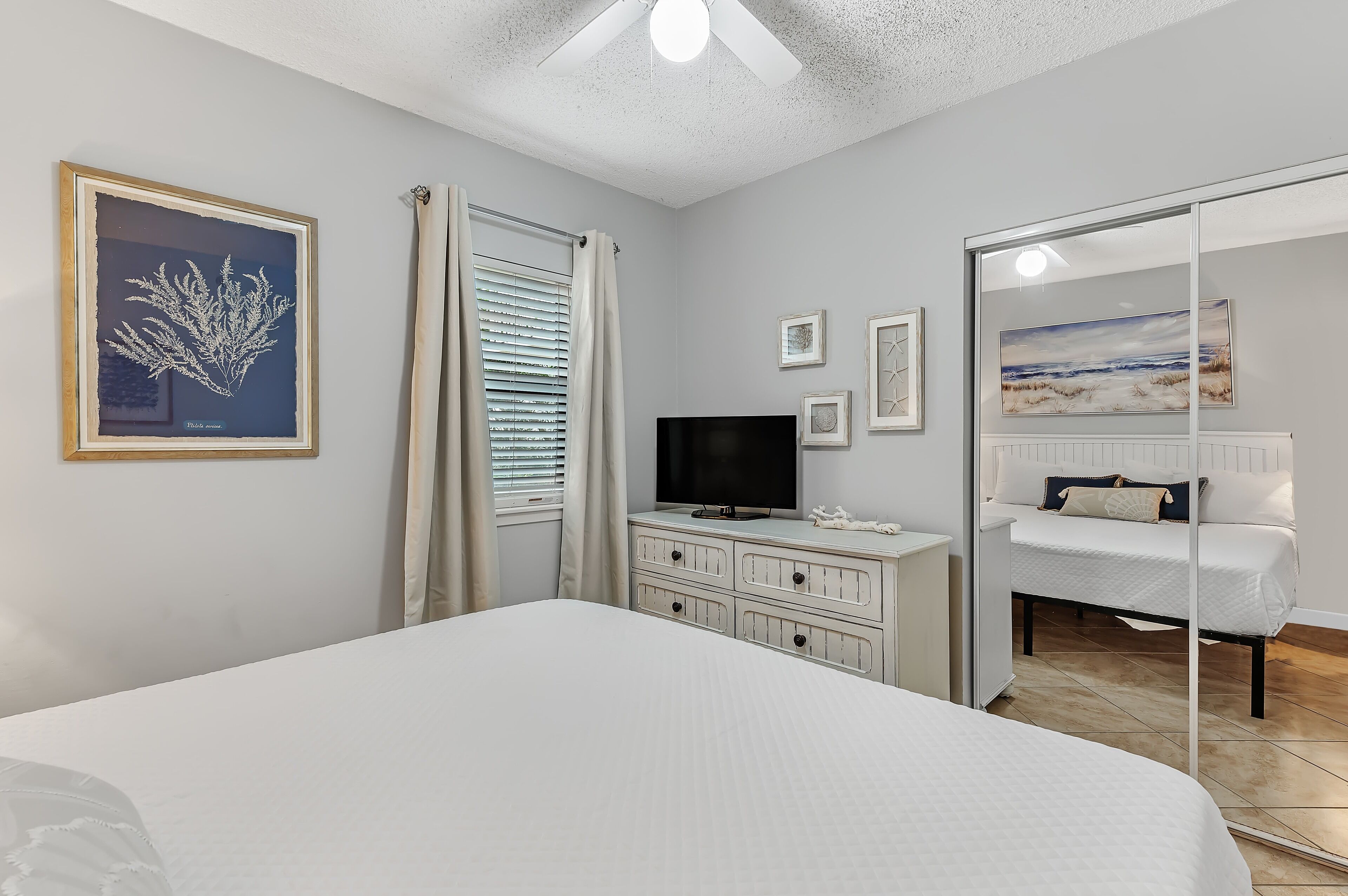 Un dormitorio con cama, cómoda, televisor y espejo.