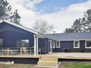 A modern building with a dark exterior, a covered patio area, and a wooden deck. - 9 Person Holiday Home in Skibby (Skibby)