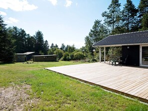 Una terraza de madera que conduce a un porche cubierto con mobiliario exterior.