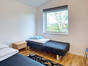 Une petite chambre avec un lit simple, une fenêtre, une table de chevet et une chaise.