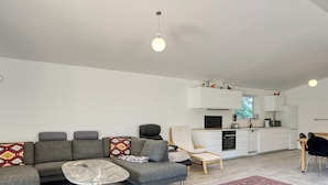 A modern living room with a grey sofa, a small round table, and a red patterned rug.