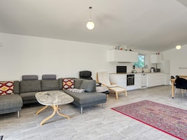 Una sala moderna con un sofá gris, una mesita redonda y una alfombra roja estampada.