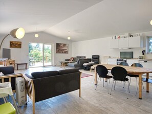 A spacious living area with a sofa, dining table, chairs, and a kitchen area with cabinets and appliances. - 9 Person Holiday Home in Skibby (Skibby)