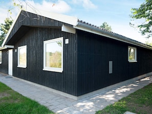 A modern building with a dark exterior, two large windows, and a sloped roof. - 9 Person Holiday Home in Skibby (Skibby)