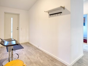 Une pièce avec un fauteuil moderne, un porte-manteau et une porte.