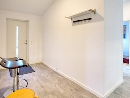 Una habitación con una silla moderna, un perchero y una puerta.