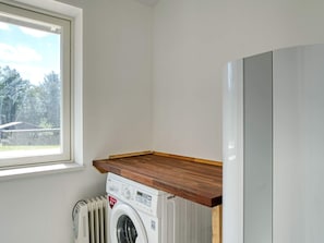 A laundry room with a washing machine, dryer, and a window with a view of trees. - 9 Person Holiday Home in Skibby (Skibby)