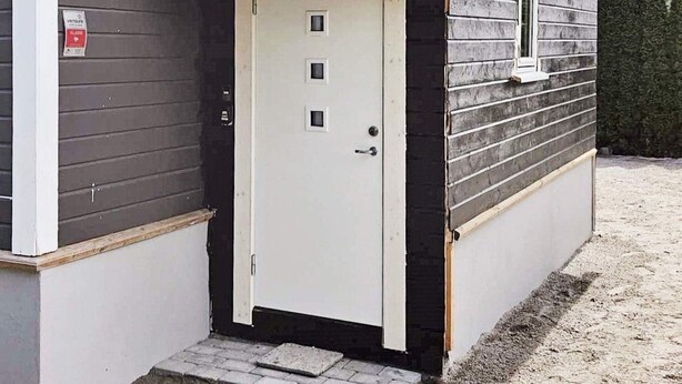 Un pequeño edificio de una sola planta con una puerta blanca y un pequeño porche.