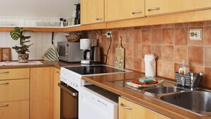 Una cocina con armarios de madera, microondas, cafetera y lavavajillas.
