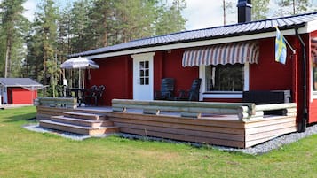 A red building with a porch, outdoor seating, and a flag.
