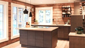 A modern kitchen with wooden paneling, a central island, pendant lights, and a view of the outdoors. - 5 Star Holiday Home in Geiranger (Stranda)