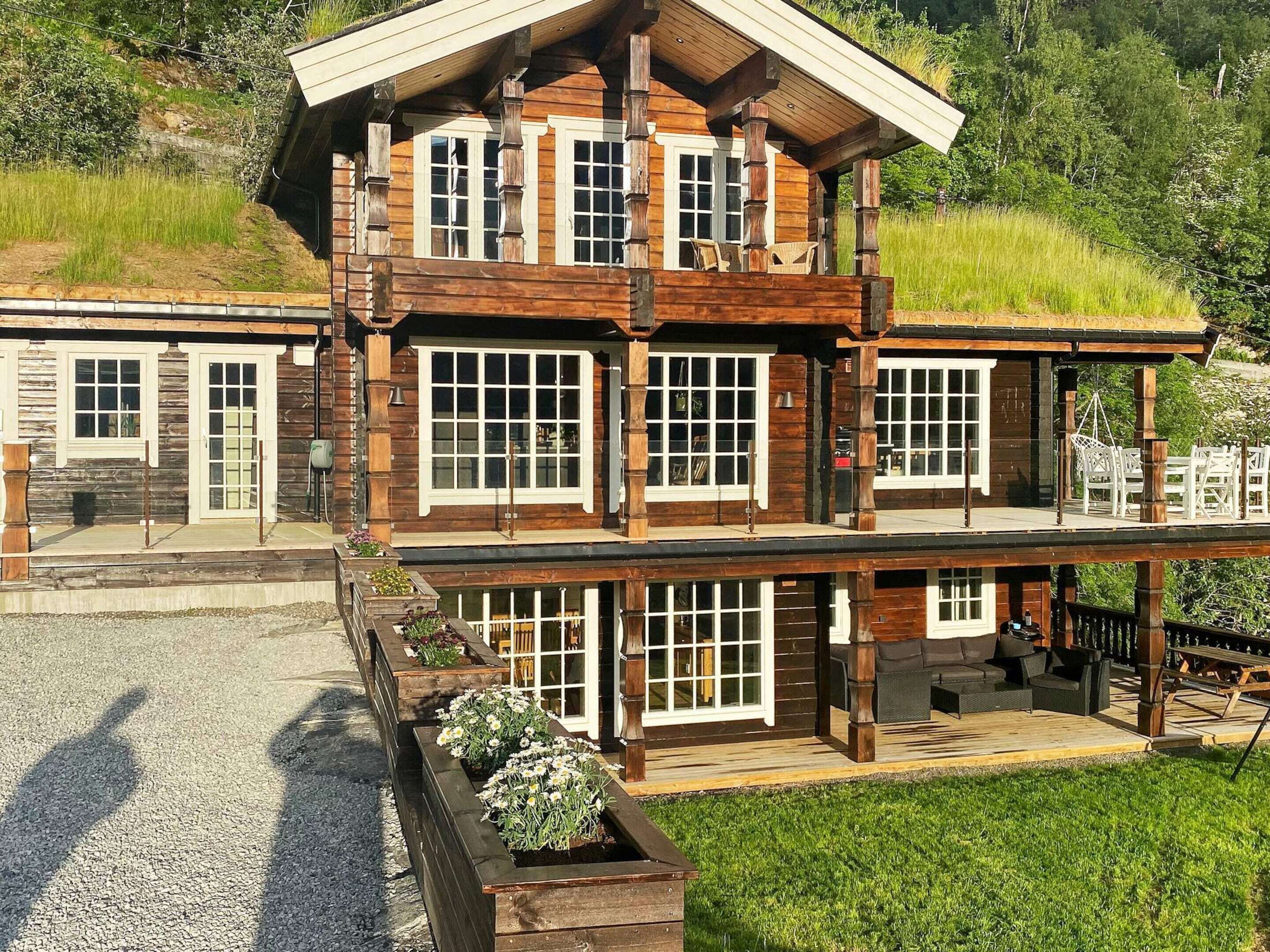 A multi-story wooden building with large windows, a covered porch, and outdoor seating.