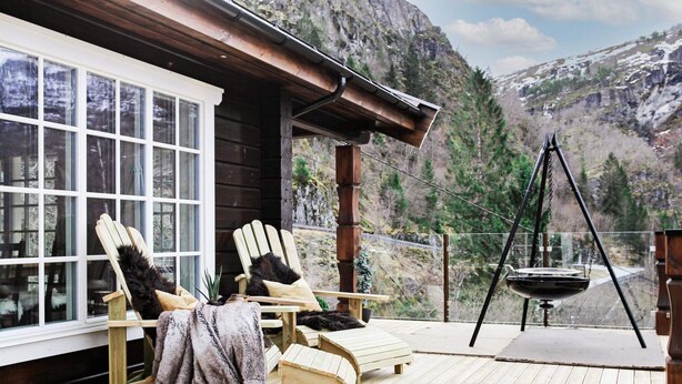 A wooden deck with two Adirondack chairs, a hanging chair, and a swing set. - 5 Star Holiday Home in Geiranger (Stranda)