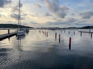 Un port de plaisance avec des bateaux amarrés, une eau calme et un ciel nuageux.