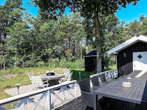 A wooden deck with outdoor furniture, a small shed, and a tree in the background. - 5 Star Holiday Home in Laeso (Læsø)
